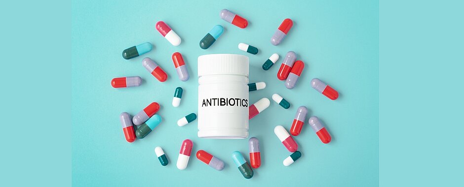 Die Abbildung zeigt eine weiße Medikamentendose und drumherum viele Pillen.