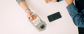Person hält elektronischen Manometer, andere Person misst die Zeit