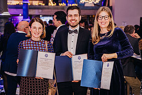 Preisträger und Preisträgerinnen halten freudestrahlend die Urkunden hoch. 
