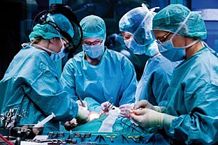 vier Chirurginnen und Chirurgen bei einer Operation