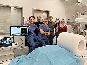 Das Team freut sich über die gelungene erste MPI-Bildgebung am Menschen und steht glücklich hinter dem Scanner.