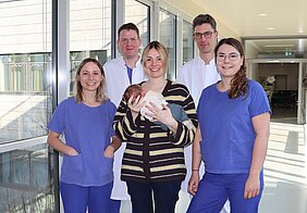 Gruppenfoto des Behandlungsteams mit Mutter Antonia Krißmer und Sohn Levi. Neben ihnen stehen die Anämie Nurses Lisa Eberle (links) und Karina Reinhard, dahinter Prof. Dr. Peter Kranke (links) und Prof. Dr. Patrick Meybohm. © Annika Wolf / UKW