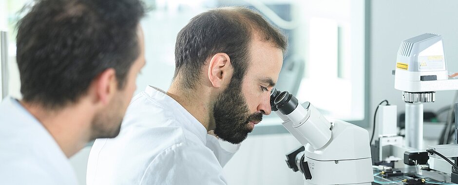 Vasco Sequeira im Labor mit weißem Kittel am Mikroskop 