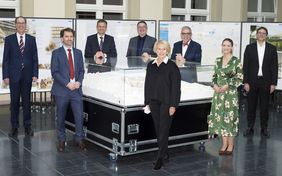 Foto zeigt Akteure des Festakts gruppiert um das Architekturmodell des Siegerentwurfs