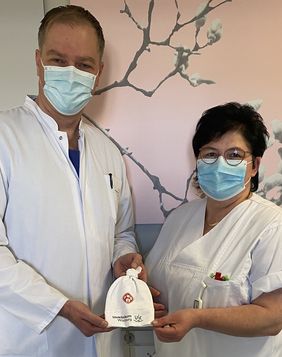 Prof. Dr. Achim Wöckel, der Direktor der Würzburger Universitäts-Frauenklinik, und die Stillberaterin Claudia Freudinger präsentieren das „Kickers-Mützchen“
