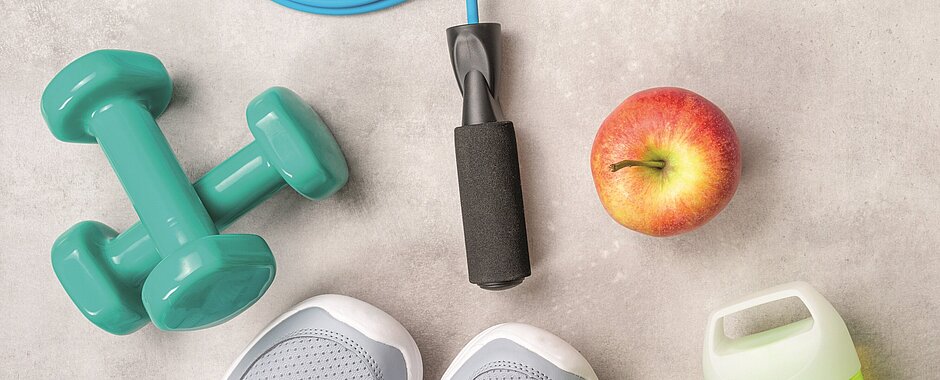 Symbolbild für gesundes Leben: Sportschuhe, Hanteln, Hüpfseil, Apfel, Wasserflasche