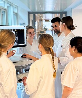 Pflegeazubis und Medizinstudierende sprechen an einem Visitenwagen