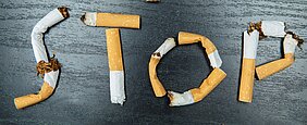 Das Wort "Stop" gelegt aus gerauchten Zigaretten