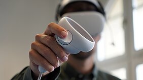 Großaufnahme des Anwenders mit VR-Brille und Hand mit Controller