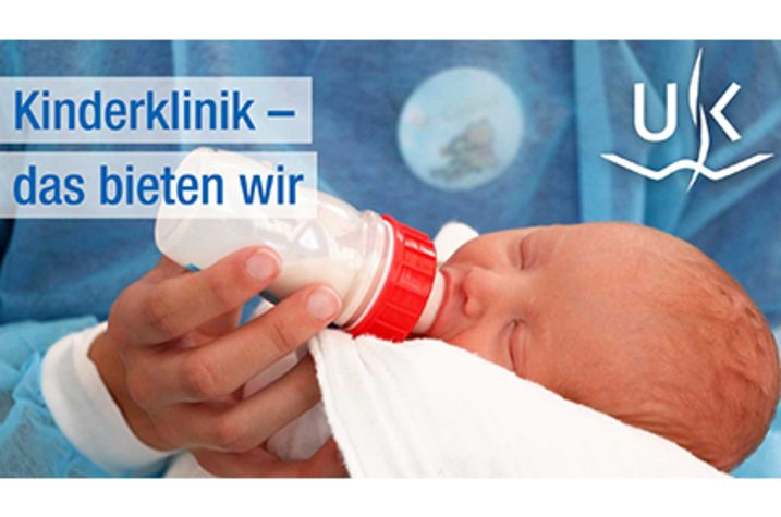 Baby, das gefüttert wird. Aufschrift: Kinderklinik. Das bieten wir.