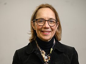 Porträtbild von Heike Rittner - sie trägt schwarzen Rolli, schwarzes Jacket und ein Tuch um den Hals 
