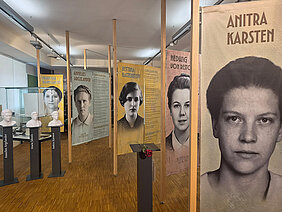 Ausstellung über Pionierinnen der Psychologie. Im Vordergrund auf einem Sockel liegt eine rote Rose und links stehen drei Sockel mit einer Büste. 