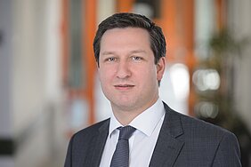 Porträtfoto von Marcel Romanos im dunkeln Anzug und mit dunkler Krawatte im Flur des Zentrums für Psychische Gesundheit 