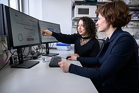 Die beiden Forscherinnen sitzen in ziviler Kleidung vor PC und diskutieren.