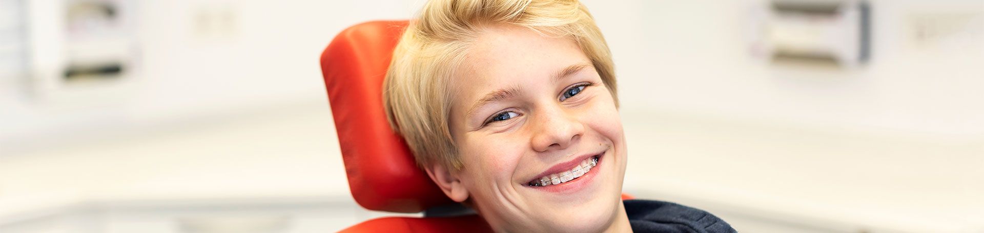 Illustrationsfoto Kieferorthopädie: Junge zeigt grinsend seine feste Zahnspange