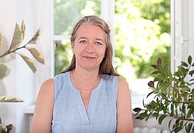 Porträtbild von Anne Simmenroth vor Grünpflanzen im Büro 