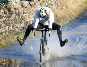 Bild: Radfahrer mit Rennrad fährt durch Pfütze