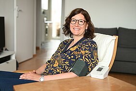 Patientin, die daheim am Wohnzimmertisch sitzt, misst ihren Blutdruck