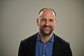 Porträtfoto von Lorenz Deserno, der ein dunkles Jacket und blaues Jeanshemd trägt. 
