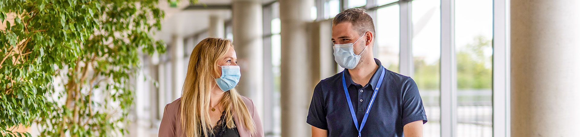 Illustrationsbild zwei Krankenhausmitarbeitende im Gespräch mit Masken auf