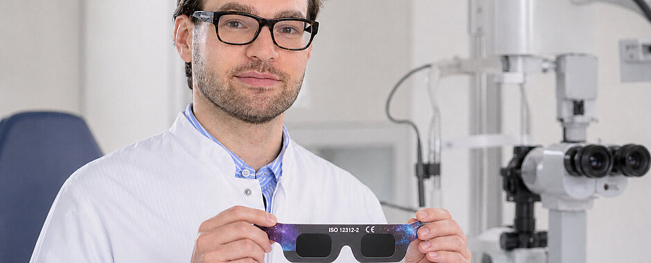 PD Dr. Berlin hält in seinen Händen eine Schutzbrille für die Sonnenfinsternis