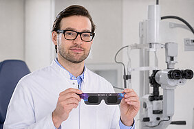 PD Dr. Berlin hält in seinen Händen eine Schutzbrille für die Sonnenfinsternis