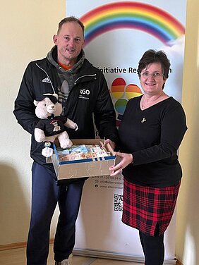 Thorsten Ellmauer und Denise Lampert bei der Spendenübergabe mit einer Kiste Bargeld und einem Teddy.