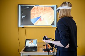 Game-Developerin mit VR-Brile und Endoskop vor Monitor.