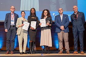 Gruppenbild auf der Bühne mit den drei Preisträgerinnen, die Urkunden und Trophäen in den Händen halten, sowie Vertretern von EFIC und Grünenthal.