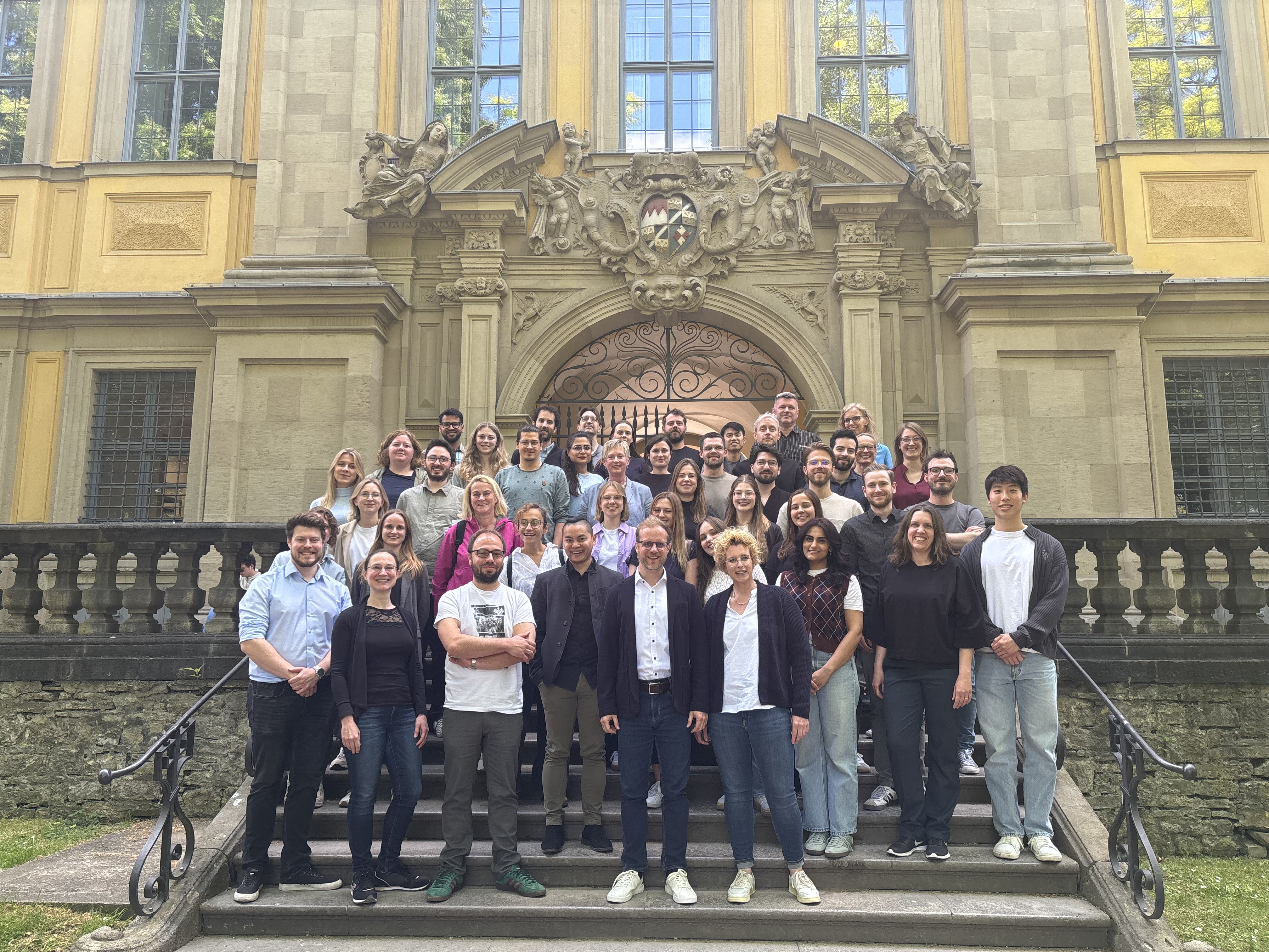 Gruppenfoto der 50 Teilnehmenden beim Retreat des Lehrstuhls für zelluläre Immuntherpie. Die Gruppe steht hintereinander aufgereiht auf einer Treppe vor einem steinernen Gebäude.