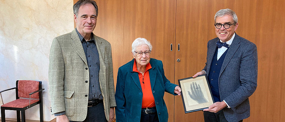 Foto zeigt Professor Michael Stolberg (links), Leiter des Instituts für Geschichte der Medizin, und Professor Matthias Frosch, Dekan der Medizinischen Fakultät, mit der Urenkelin Albert von Köllikers.