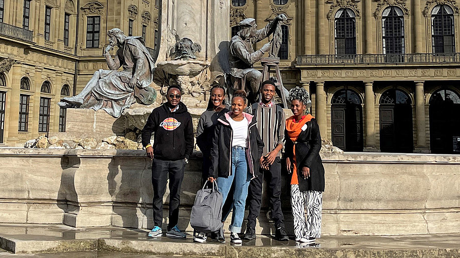 Die Austauschstudierenden aus Mwanza bei einem Rundgang durch Würzburg am Frankoniabrunnen vor der Residenz. 