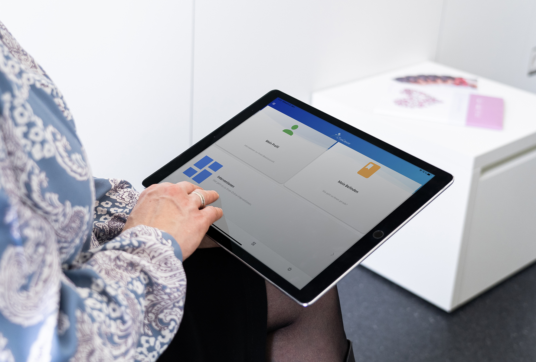 Eine Brustkrebspatientin hält ein Tablet mit der BETTER CARE App in den Händen. 