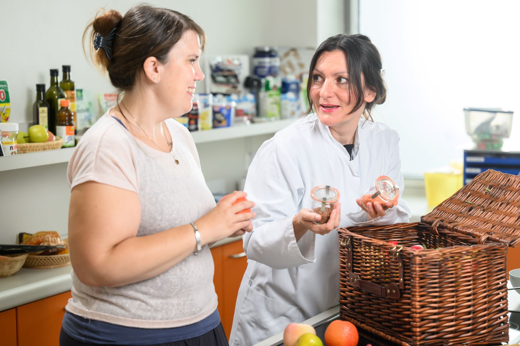 Studienteilnehmerin und Studienärztin beugen sich über Obstkorb in der Diätküche