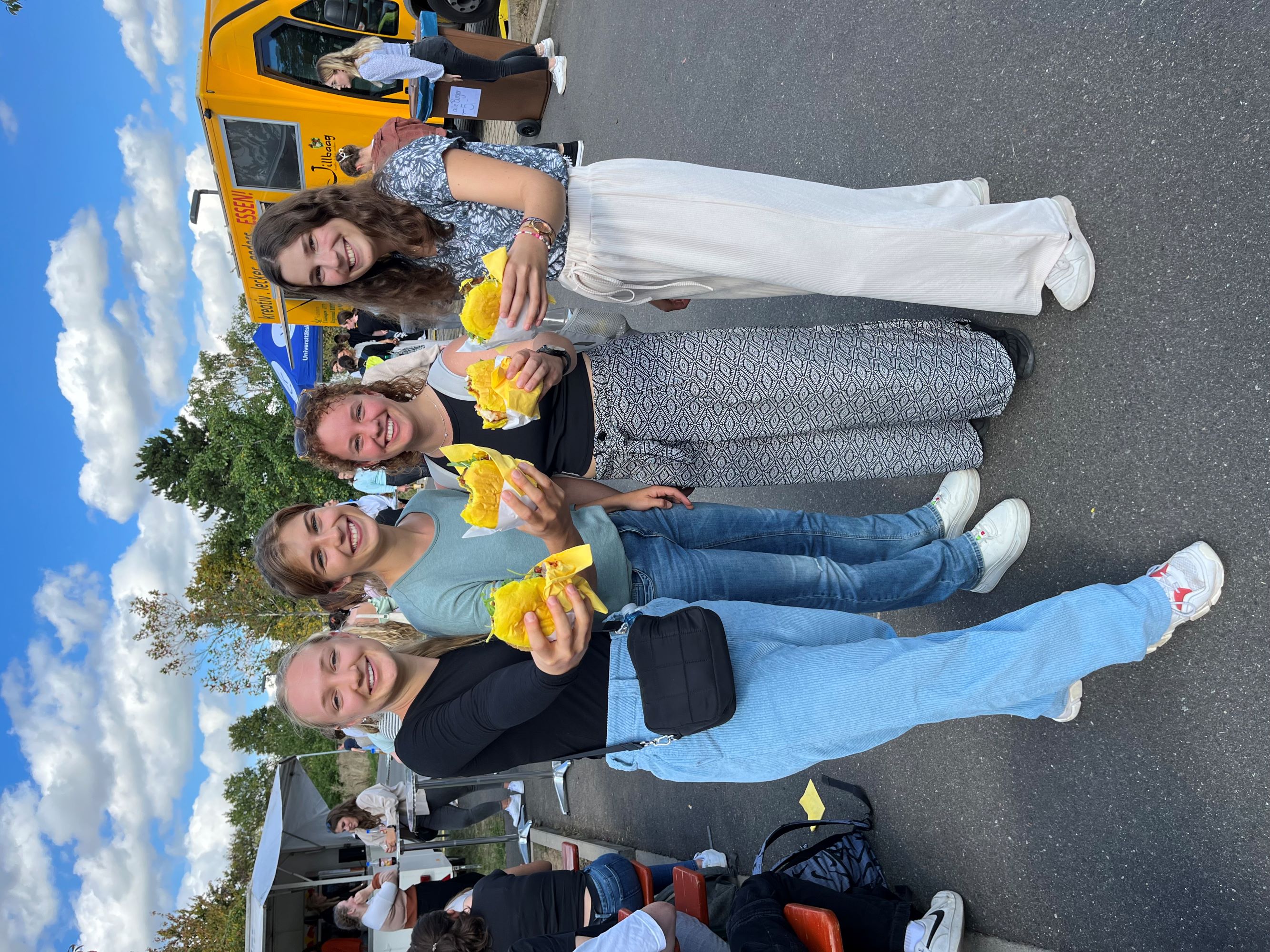 4 Azubis mit Burger vom Food-Truck bei Azubi-Welcome-Party