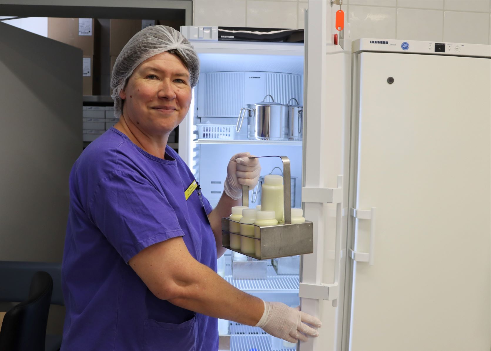 Sylvia Königer stellt einen Träger mit Muttermilchflaschen in den Kühlschrank. 