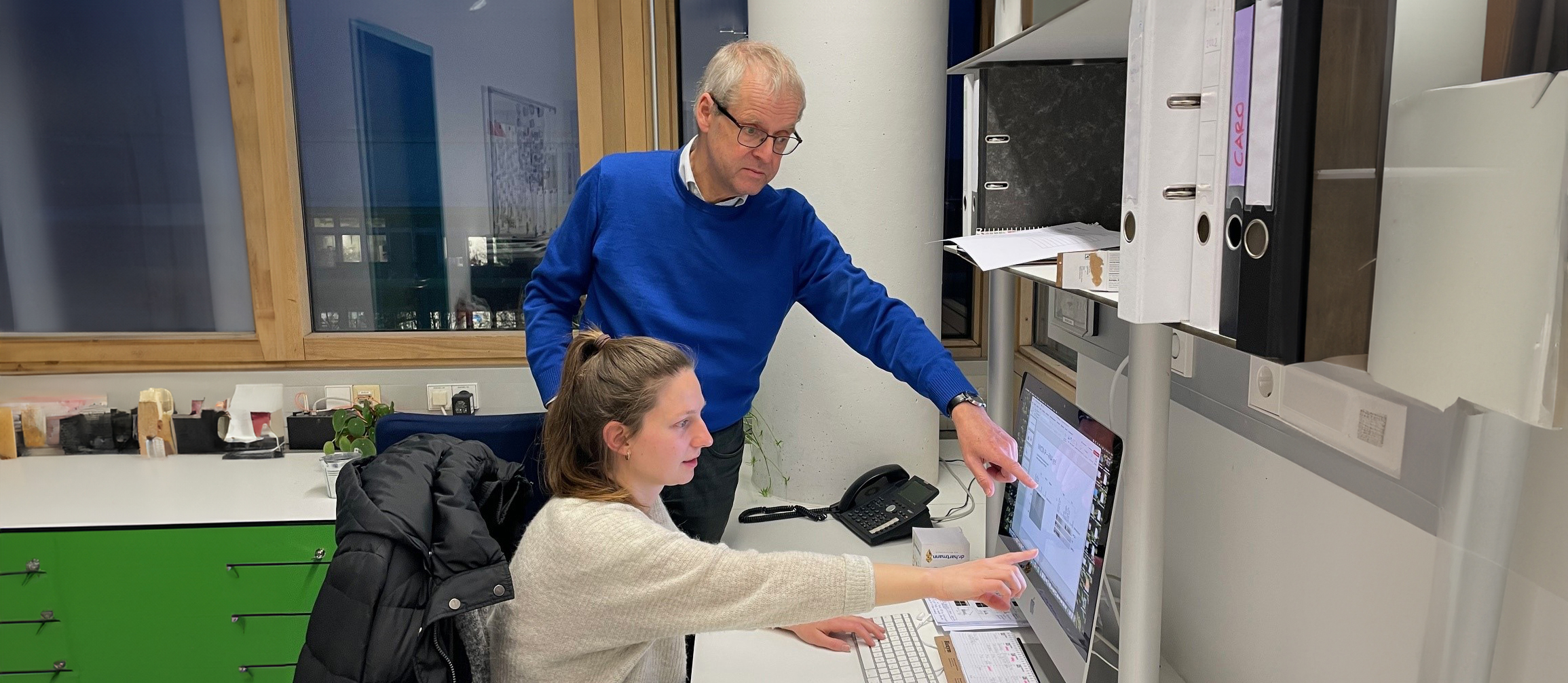 Martin Eilers und Katrin Trunk zeigen auf einen Bildschirm. 