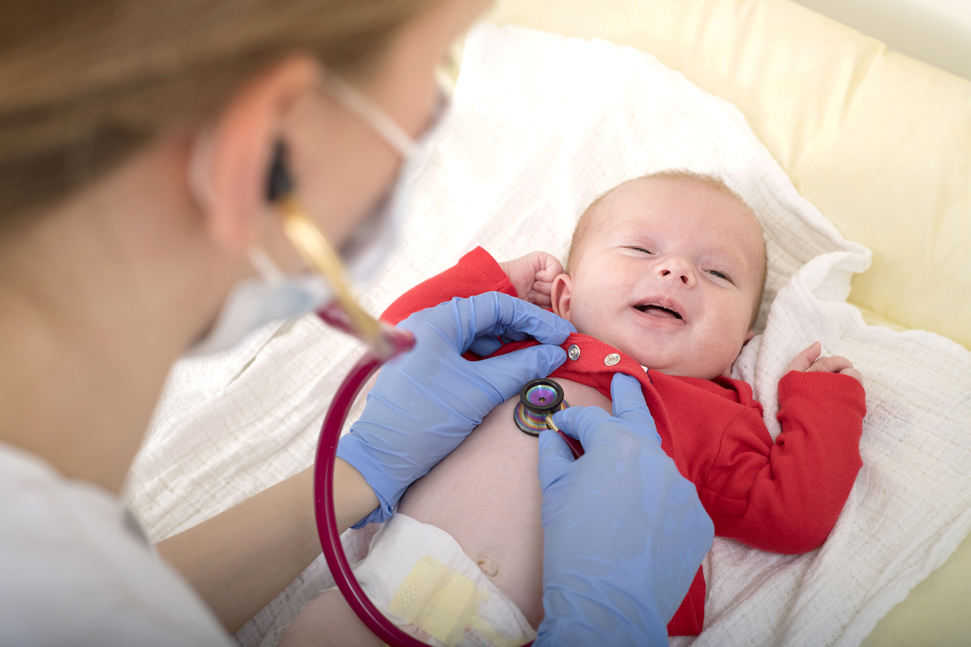Ein Baby wir mit einem Stethoskop an der Brust abgehört 