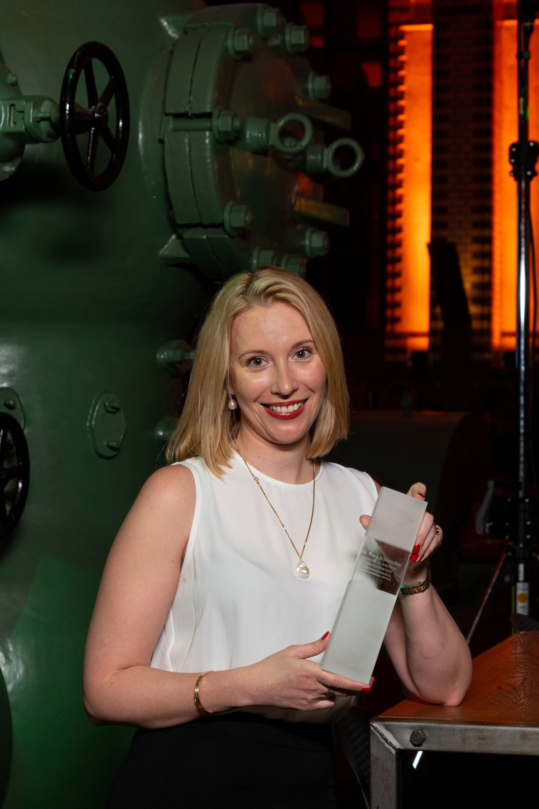 Nora Schorscher hält den gläsernen Preis in den Händen, im Hintergrund die Atmosphäre des Wasserwerks in Berlin 