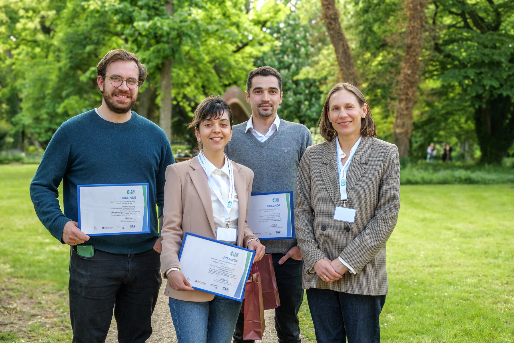 Gewinnerin und Gewinner mit Urkunden stehen im Garten mit Sprecherin des TWINSIGHT-Kollegs