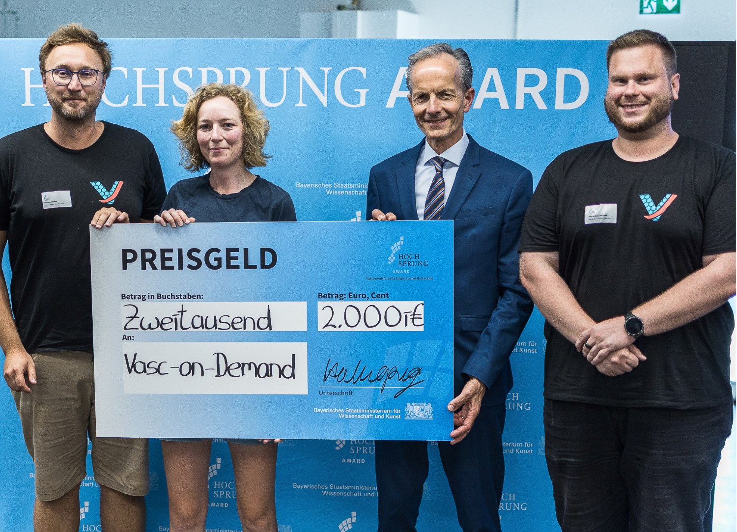 Die Gewinner und Preisverleiher posieren mit überdimensional großem Scheck über 2.000 Euro 