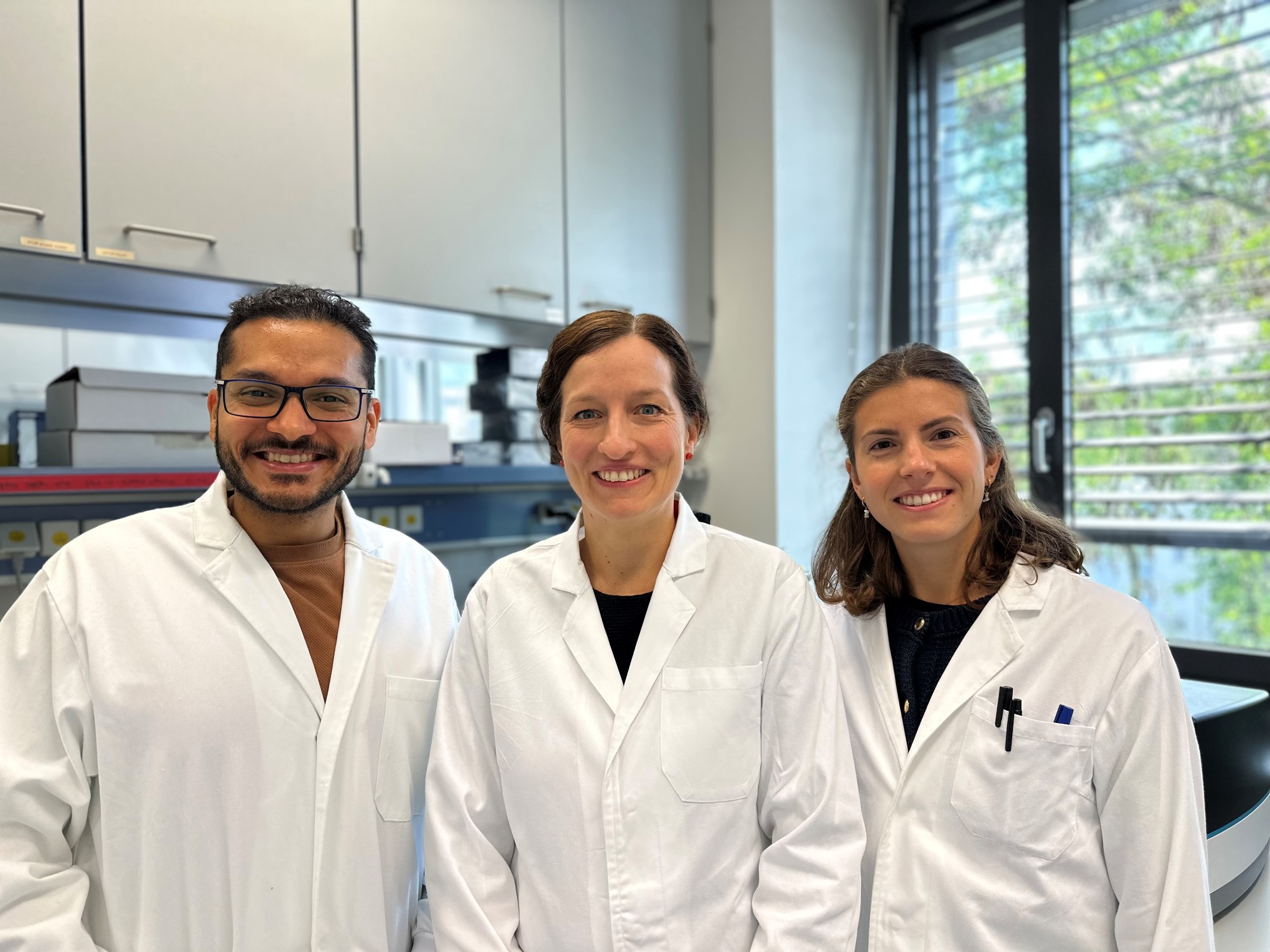 Angela Riedel Studienteam: Angela Riedel, Moutaz Helal und Greta Mattavelli im stehen in weißen Kitteln im Labor. 