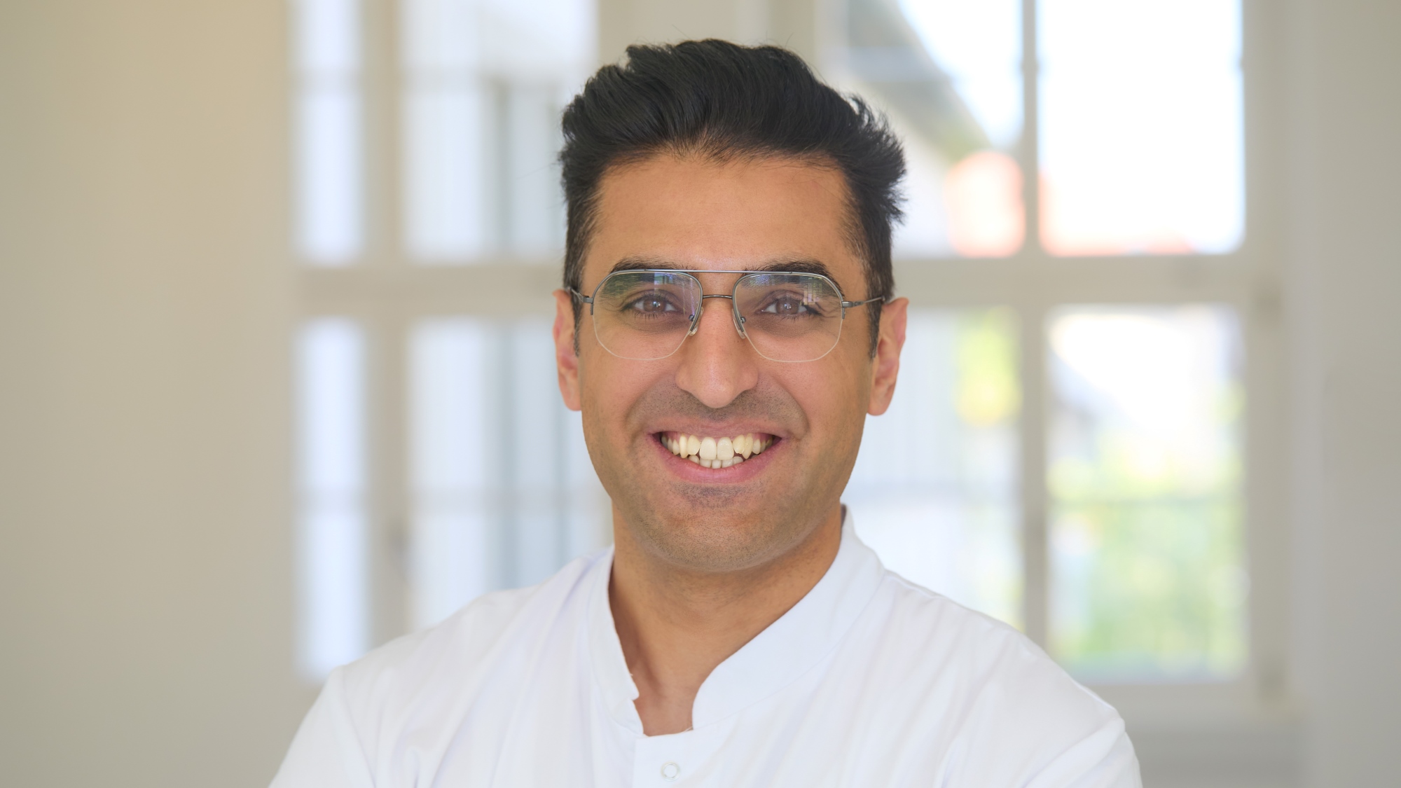Ugur Uslu Porträtbild von Ugur Uslu mit Kittel im Flur der Dermatologie