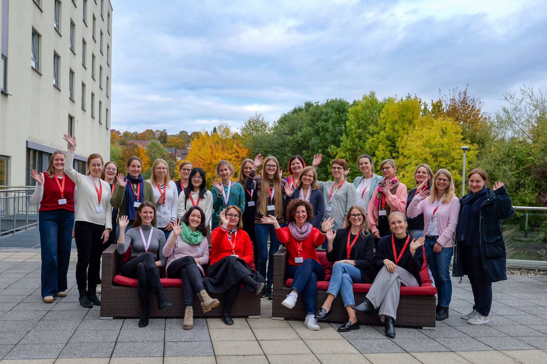 Die Teilnehmerinnen posieren draußen auf einer Hotelterrasse fürs Bild und winken -  vorne sitzen sechs Frauen auf zwei Sofas, dahinter gruppieren sich die anderen Frauen 