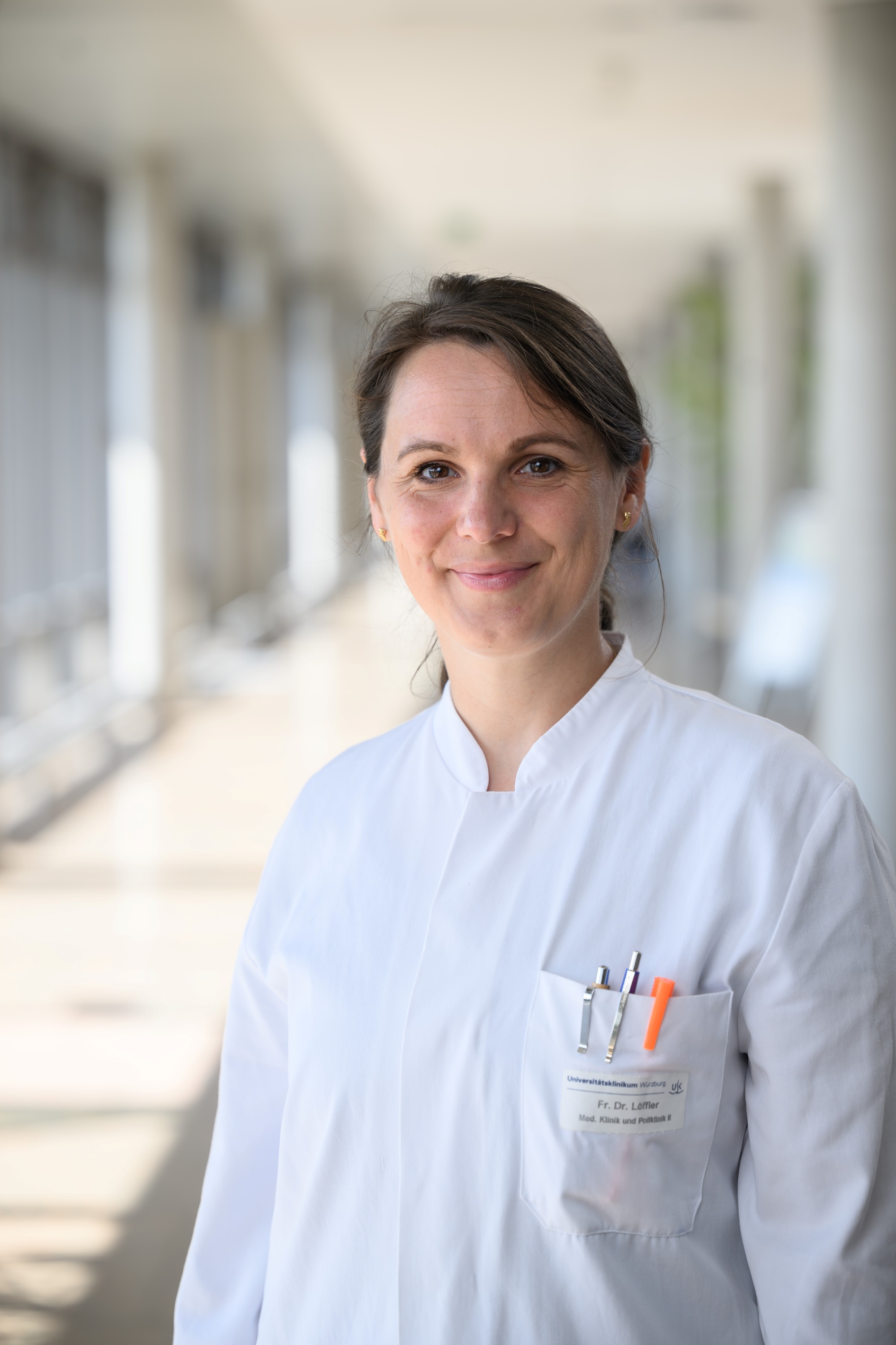 Porträt von Prof. Dr. Claudia Löffler in weißem Kittel - hinten ist unscharf der Gang im ZIM ZOM zu erkennen.