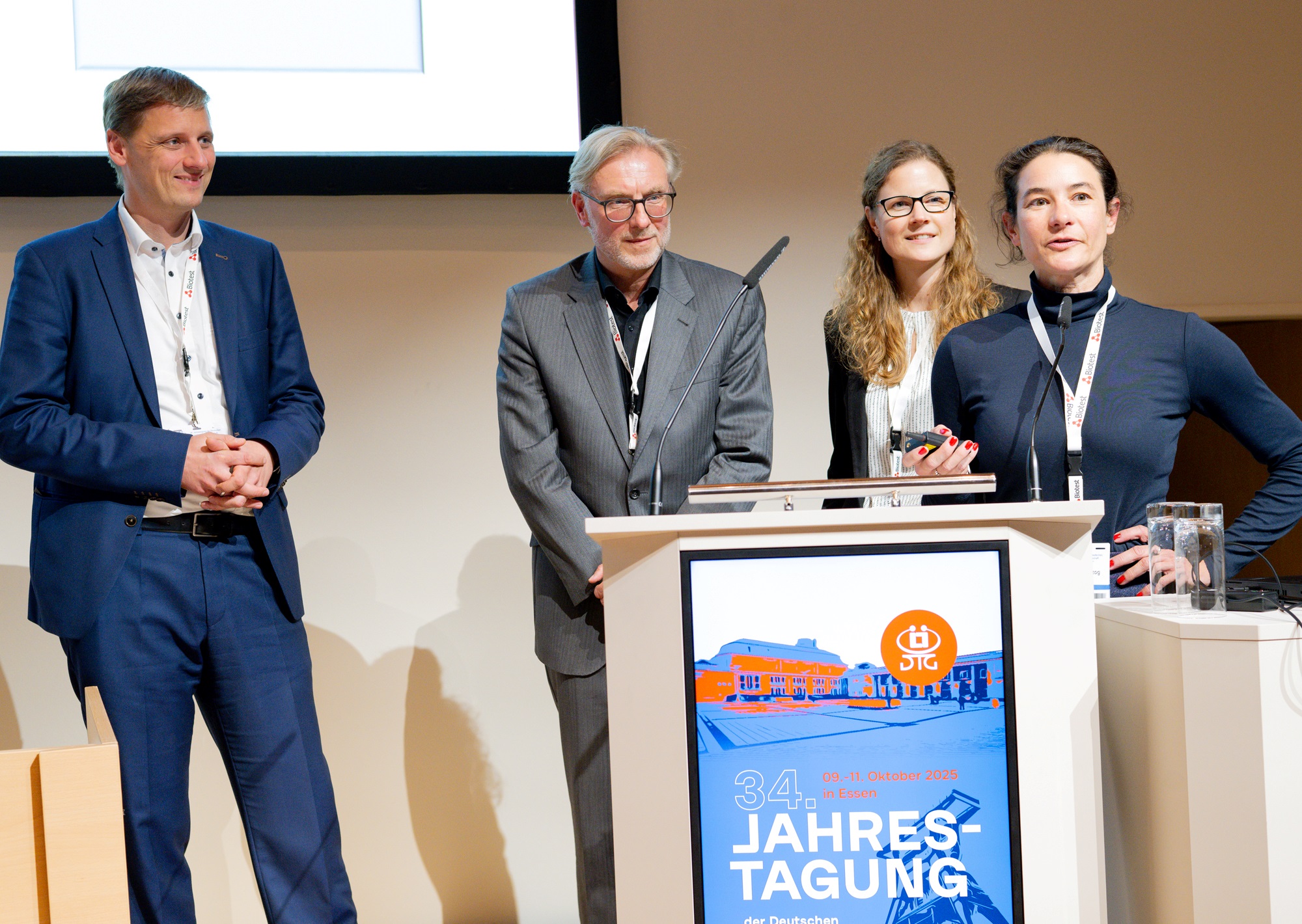 Bild zeigt Herrn Prof. Lock, Herrn Prof. Lopau, Frau Dr. Wagner und Frau Dr. Herzog. Alle vier stehen an einem Pult und zeigen eine Präsentation. 