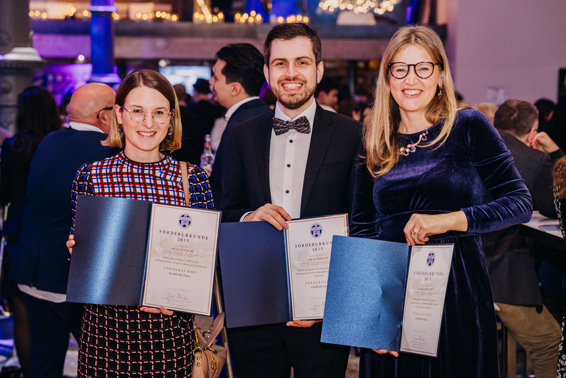 Preisträger und Preisträgerinnen halten freudestrahlend die Urkunden hoch. 