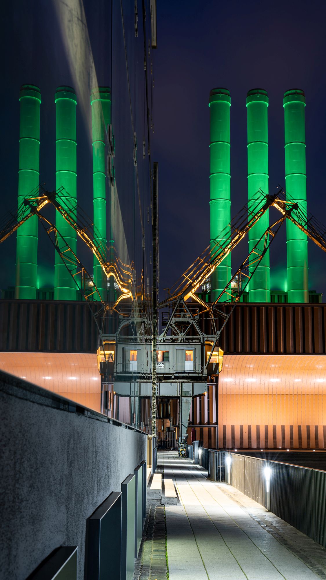 Kamine des Würzburger Heizkraftwerks am Tag der Seltenen Erkrankungen, die farbig beleuchtet sind. 
