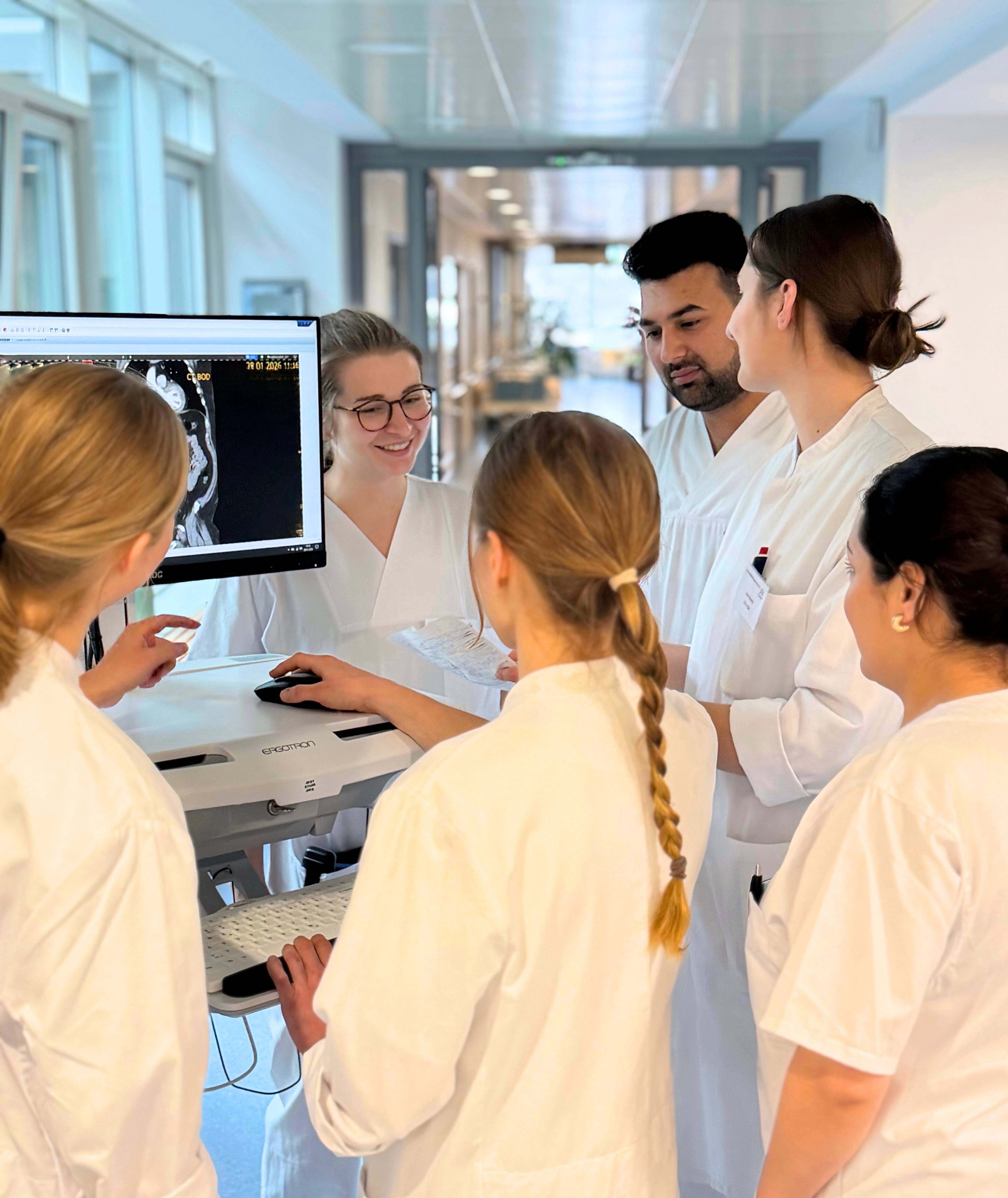 Pflegeazubis und Medizinstudierende sprechen an einem Visitenwagen