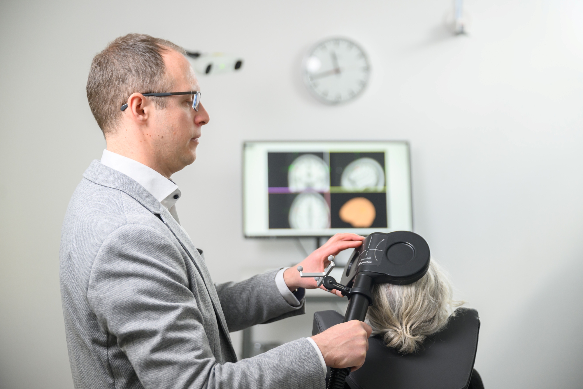 Alexander Soutschek steht im Labor und setzt einer Probandin eine Spule auf den Schädel.
